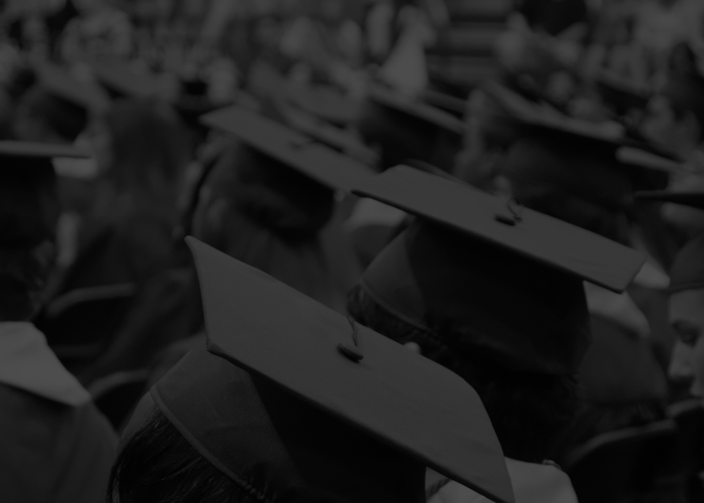 black and white photo of students sitting in graduation caps and gowns