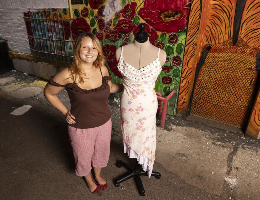Student stands next to mannequin displaying her award winning floral dress